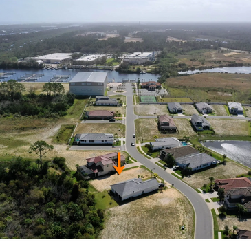 Aerial view of a suburban neighborhood with an orange arrow pointing to a specific house.