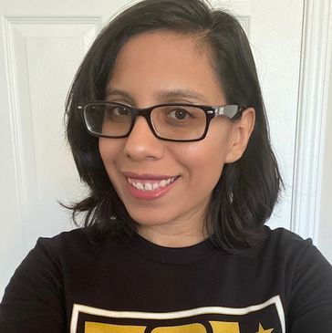 A smiling woman with glasses and shoulder-length dark hair.