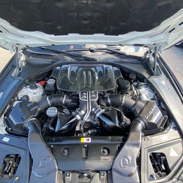 BMW engine bay with carbon fiber components under an open hood.
