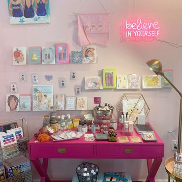 Creative workspace with art supplies and a neon "believe in yourself" sign.