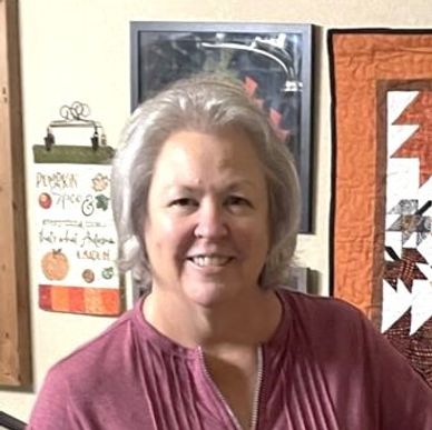 Smiling woman with gray hair in a maroon top.