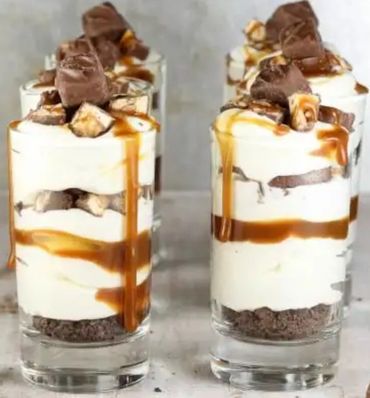 Layered dessert with cream, chocolate, and caramel in glasses.