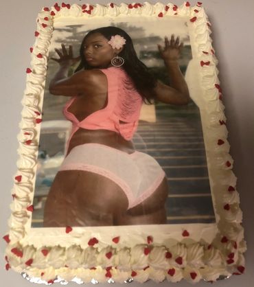 A decorated cake with an image of a woman in pink lingerie and a flower in her hair.
