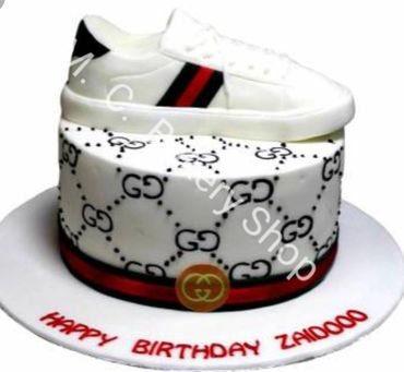 A stylish birthday cake with a sneaker design on top and Gucci-themed decorations.