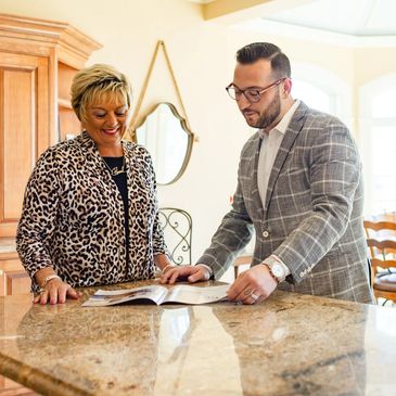 Two professionals discussing documents at a kitchen counter.