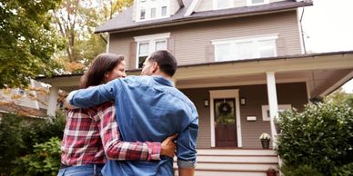 Couple embracing while looking at their new home.