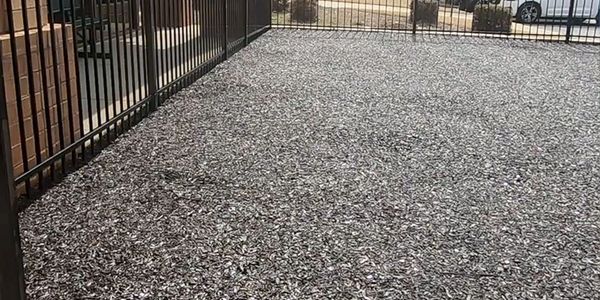 A fenced area covered with dark wood chips or mulch.