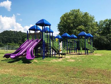 Colorful playground with purple slides and blue roofs on a sunny day.