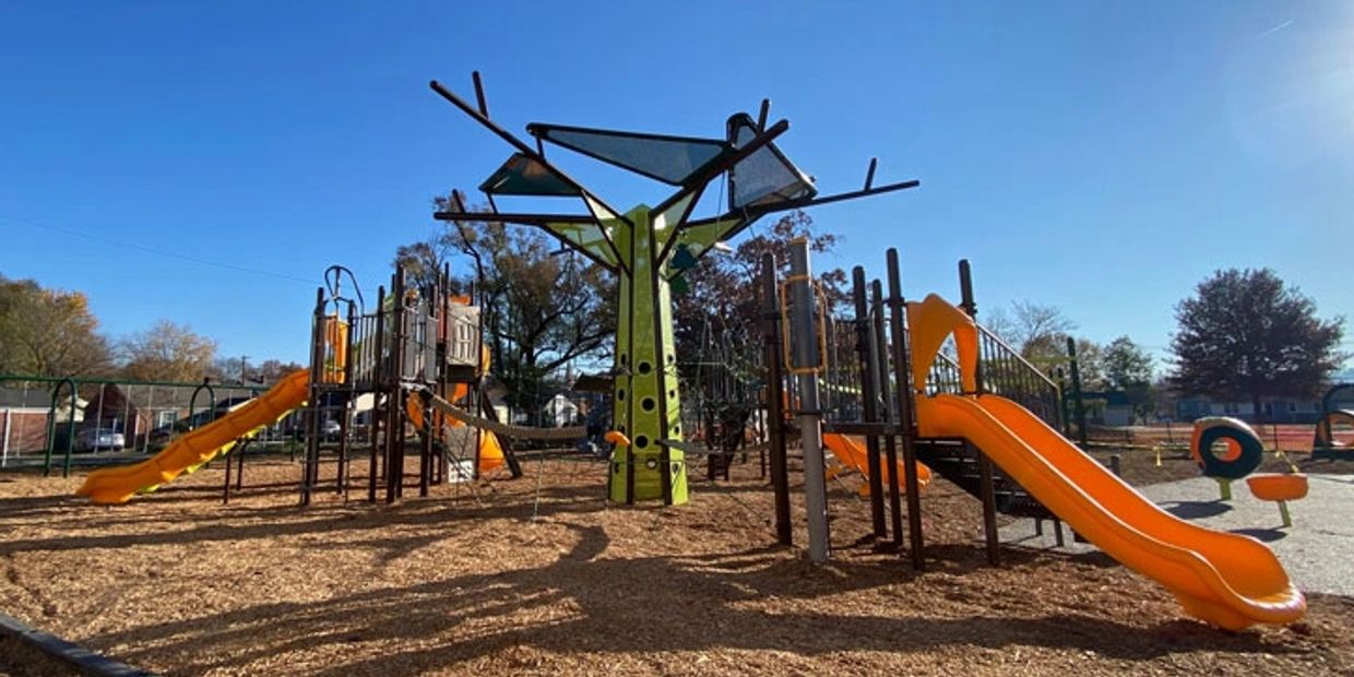 A colorful playground with slides and climbing structures under a clear blue sky.