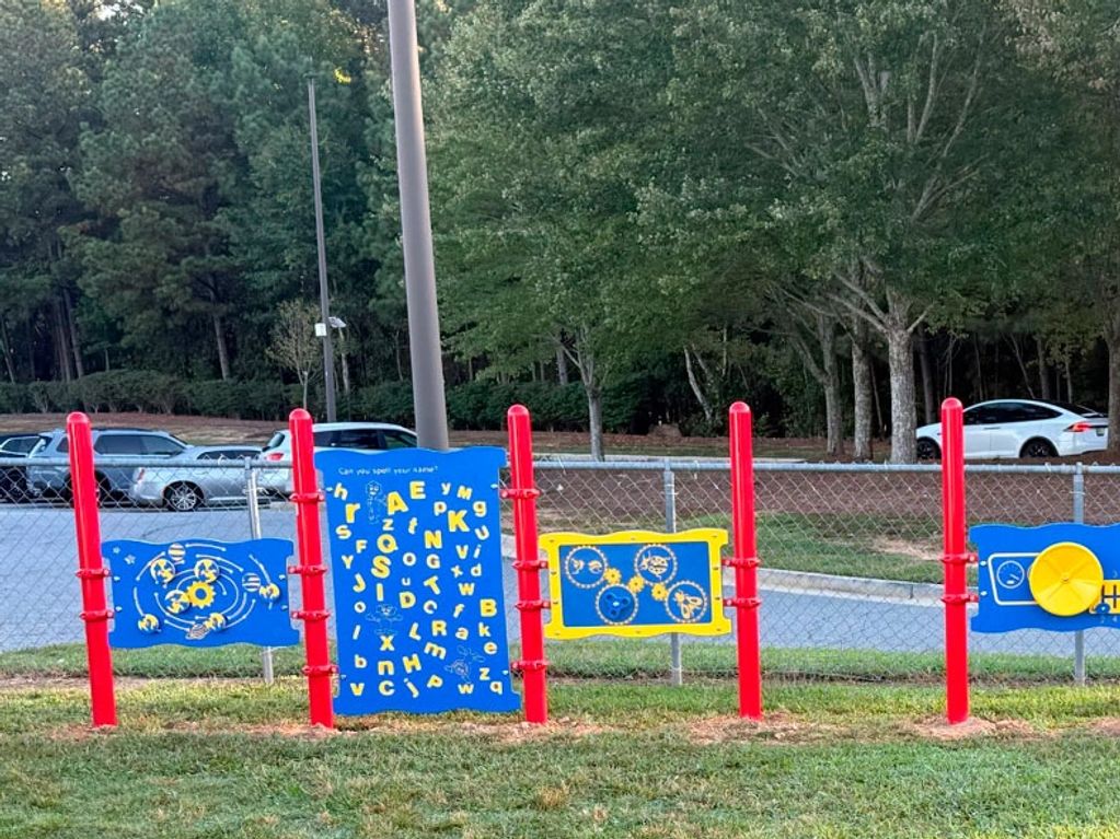 Colorful playground panels with educational activities and red posts outdoors.