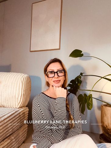Woman seated with a thoughtful expression in a cozy room.