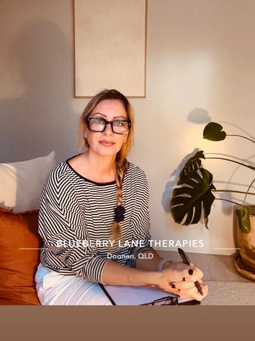 Woman with glasses sitting and writing in a cozy room.