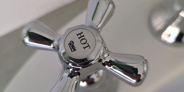 Close-up of a shiny chrome 'HOT' faucet handle.