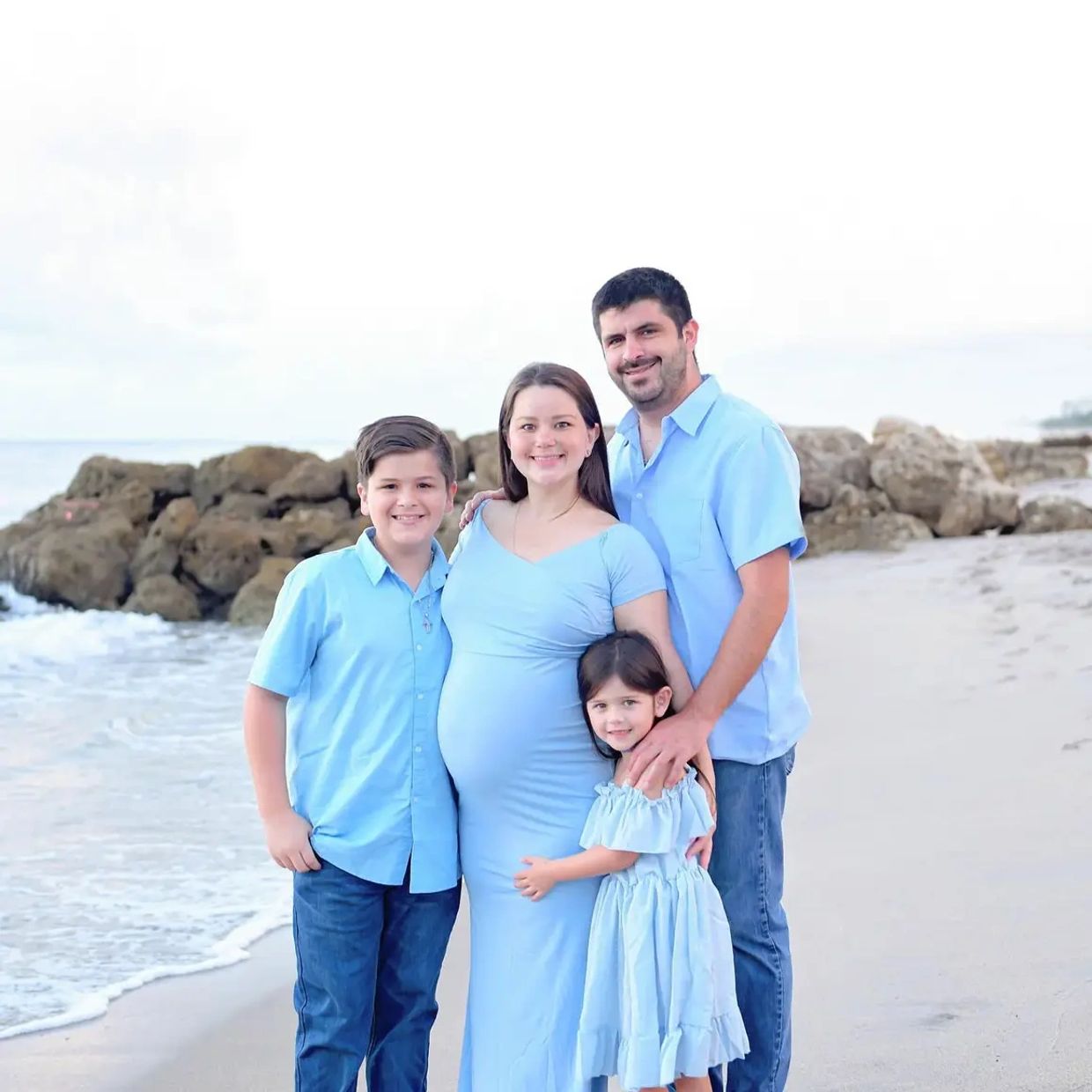 Family in matching blue outfits posing on the beach.