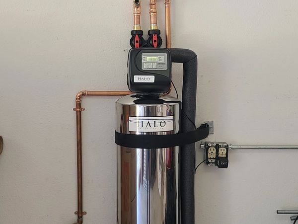 Installed water softener unit with pipes and control panel.