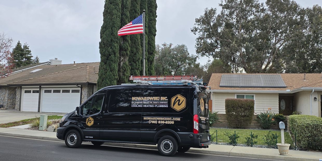 Black service van parked in front of a house with solar panels.