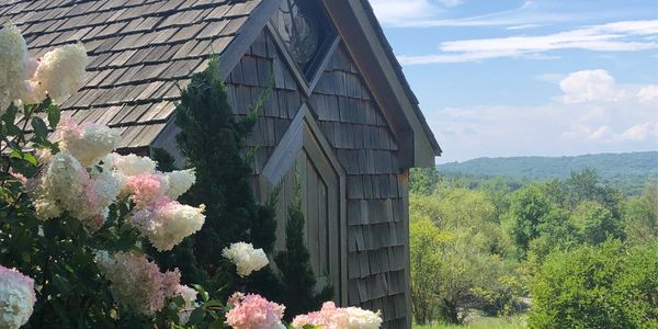 Rustic wooden house with blooming flowers and scenic countryside view.