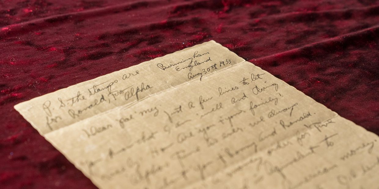 Close-up of an old handwritten letter on a red velvet surface.