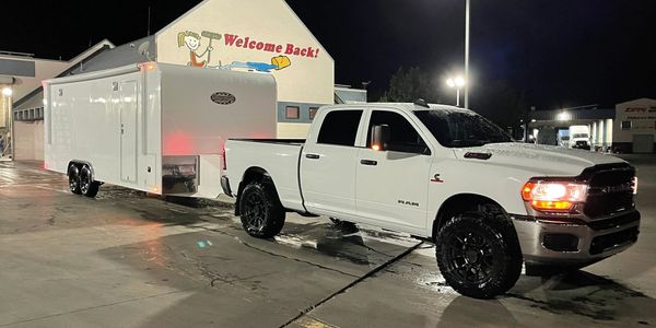 White pickup truck towing a large enclosed trailer at night.