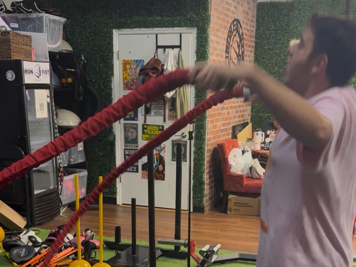 Man exercising with resistance ropes indoors.