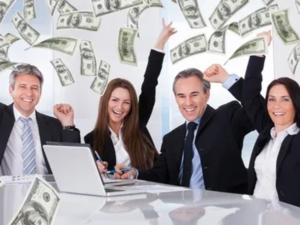 Happy business team celebrating with money falling around them.
