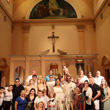 Large group posing inside a church beneath a crucifix and religious artwork.