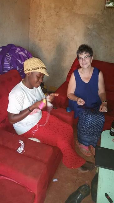 Two women sitting and smiling in a cozy room with red sofas.
