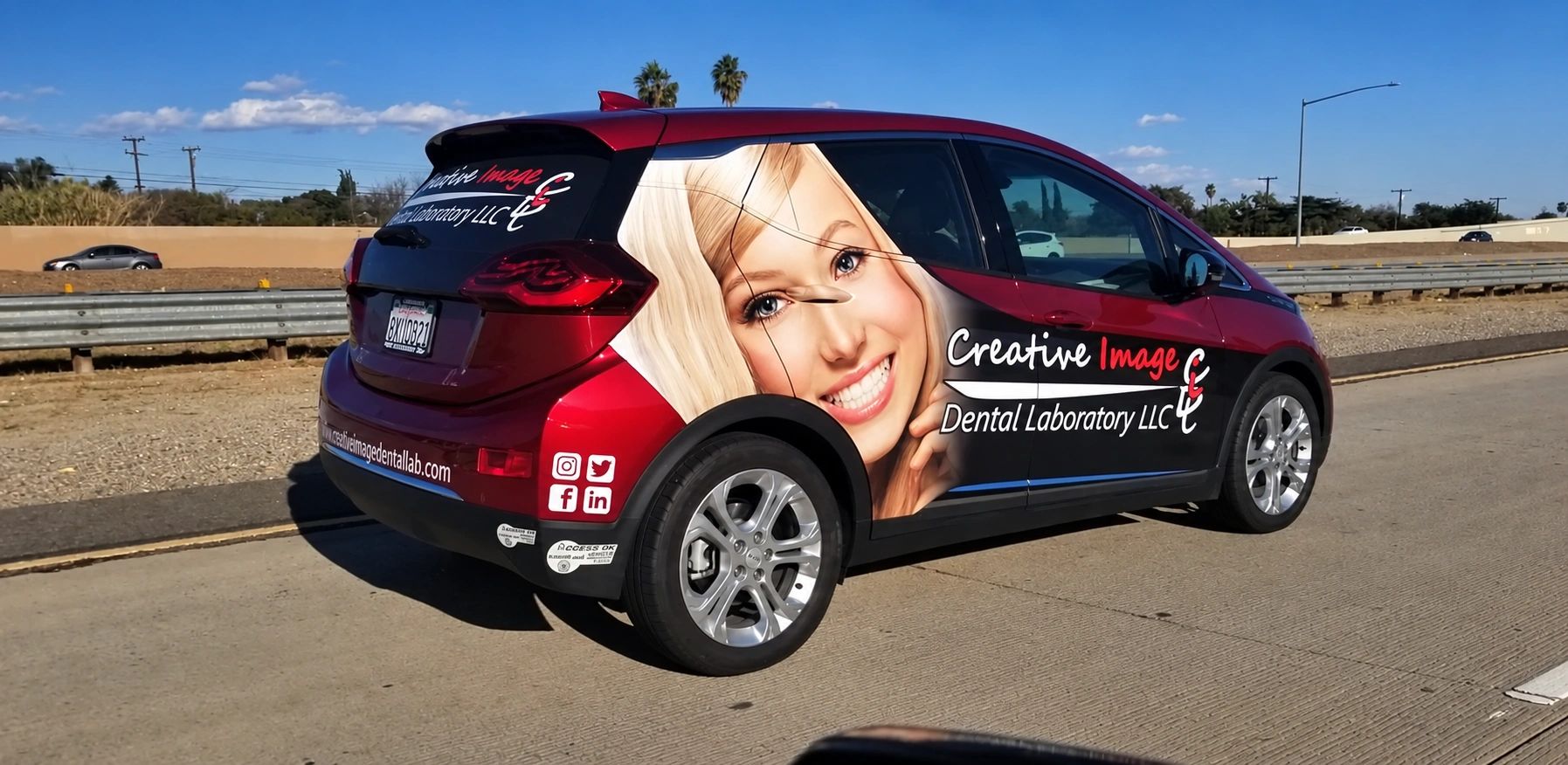 Red car with dental laboratory advertisement and smiling woman.