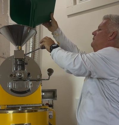 Mike Bearden pours beans into a yellow coffee roasting machine.