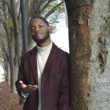 Man leaning against tree with an outreaching hand. 