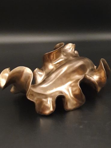 Abstract bronze sculpture with fluid, wavy design.