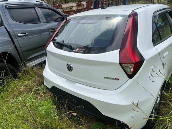 White MG3 hatchback parked beside a gray SUV in grassy area.