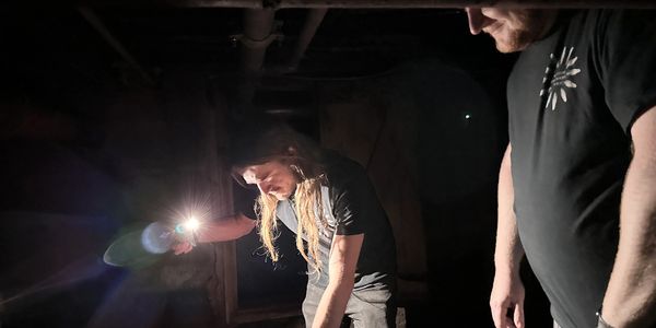 Two people exploring a dark space with a flashlight.