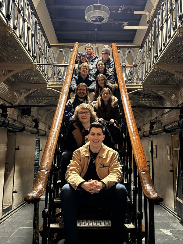 Group of friends sitting on a staircase inside a building.