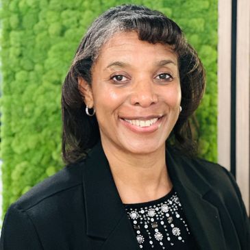Professional woman smiling in front of a green textured background.