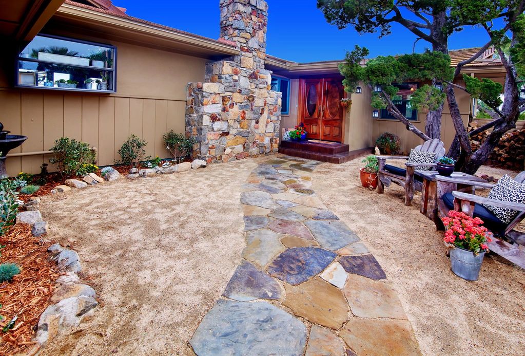 After: A courtyard with new stone walkways and chairs under the shade of a tree
