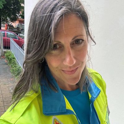 Woman in bright yellow jacket smiling outdoors.