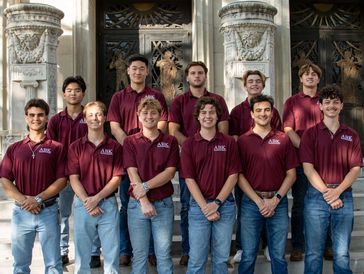 Aggie Business Kings spring class of 2025 smiling in front of administration building.