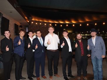 Aggie Business Kings members doing a thumbs up at a formal event.