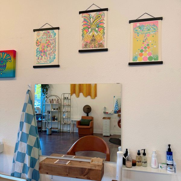 Artistic salon corner with vibrant prints and cozy styling chair.