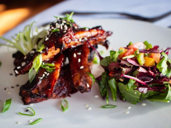 Barbecue ribs garnished with sesame seeds and scallions served with a fresh mixed salad.