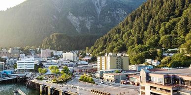 A scenic town nestled between lush green mountains and a waterfront.