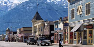 Small town street with vintage buildings and mountain backdrop.