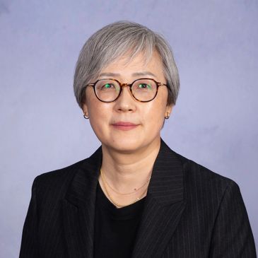 Professional woman with short gray hair and glasses in a black blazer.