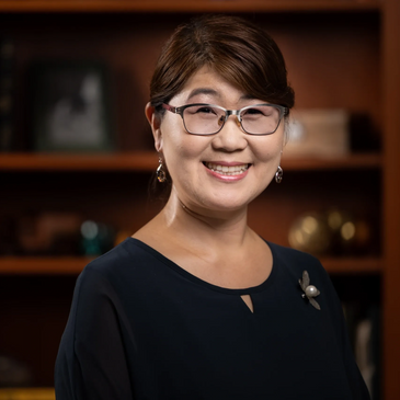 Smiling woman wearing glasses and elegant earrings.