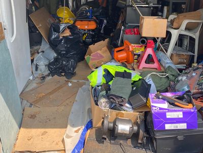 Garage filled with junk fridge cardboard boxes wood metal motors electronics plastic old tools. 
