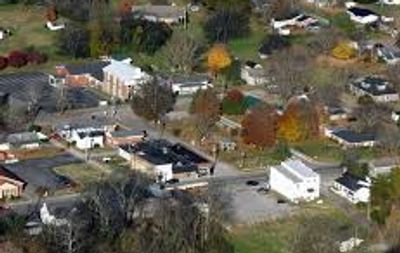 Aerial view of a small town with buildings, streets, and autumn-colored trees.