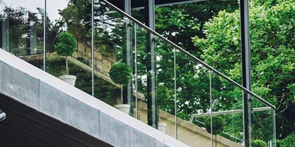 Modern balcony with glass railing and green plants.