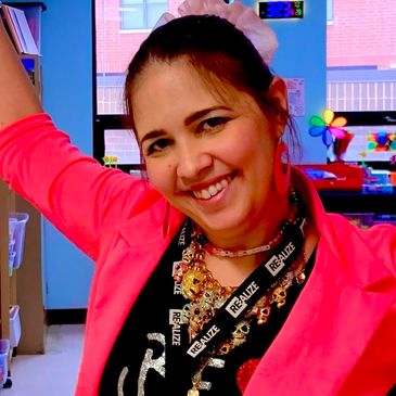 Smiling woman wearing a bright pink jacket and accessories.