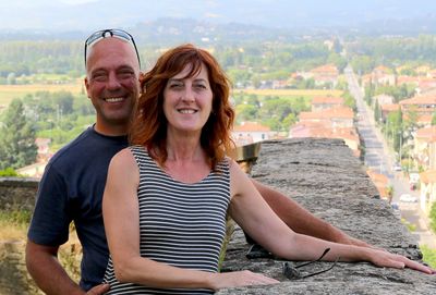 man and a woman with arms on a stone wall 